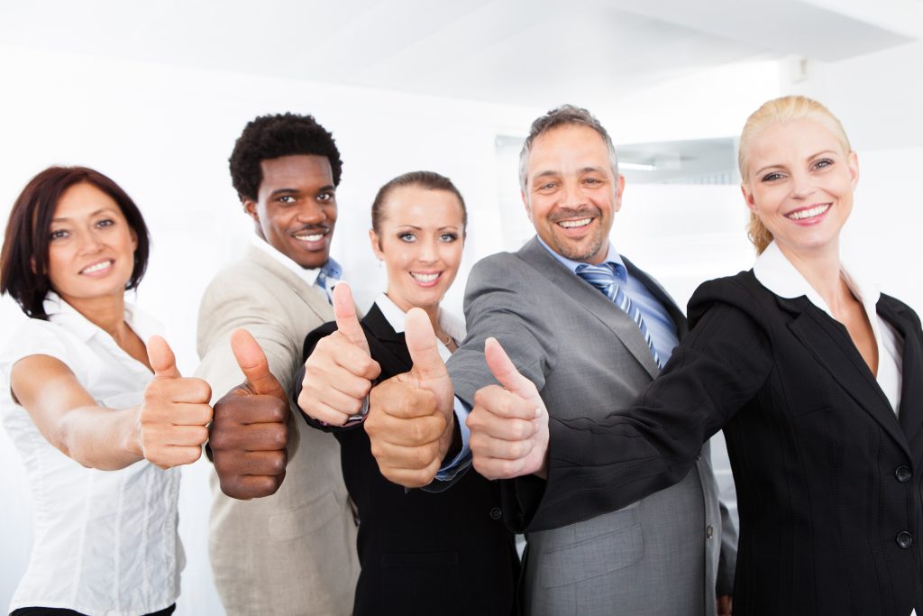 a group of people in suits together, smiling at the camera with thumbs up