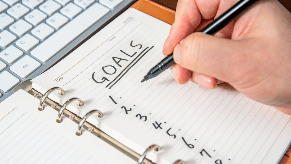A pad being written on with 'goals' and number 1-9 written on it